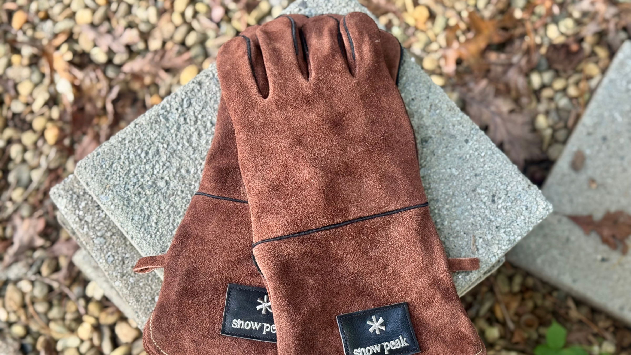 pair of brown leather Snow Peak Fire Side Gloves on top of cinder block outside